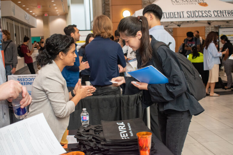 Student looking at company's information card during conversation with company representative.